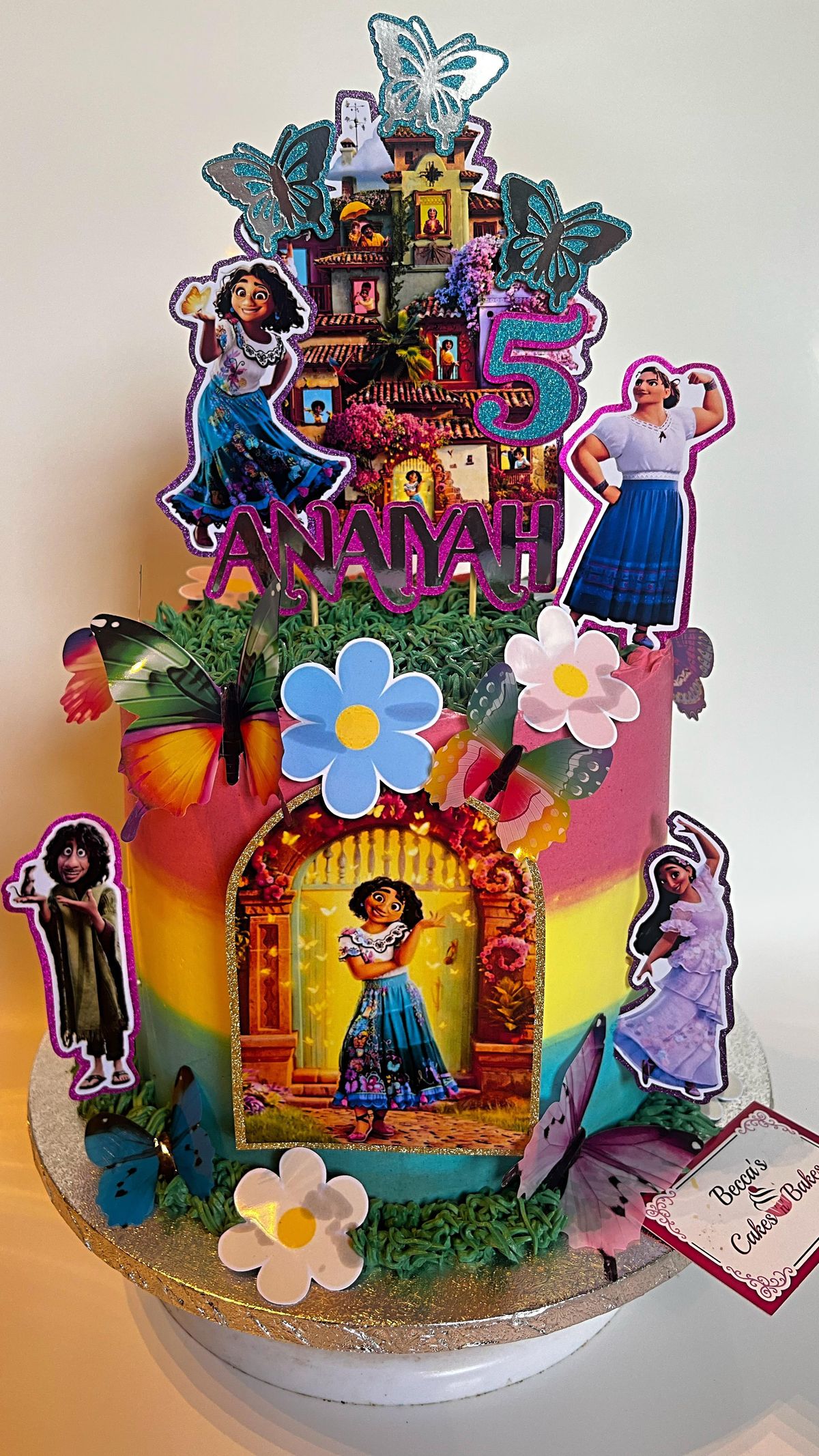 A colourful Encanto-themed kids birthday cake with character toppers