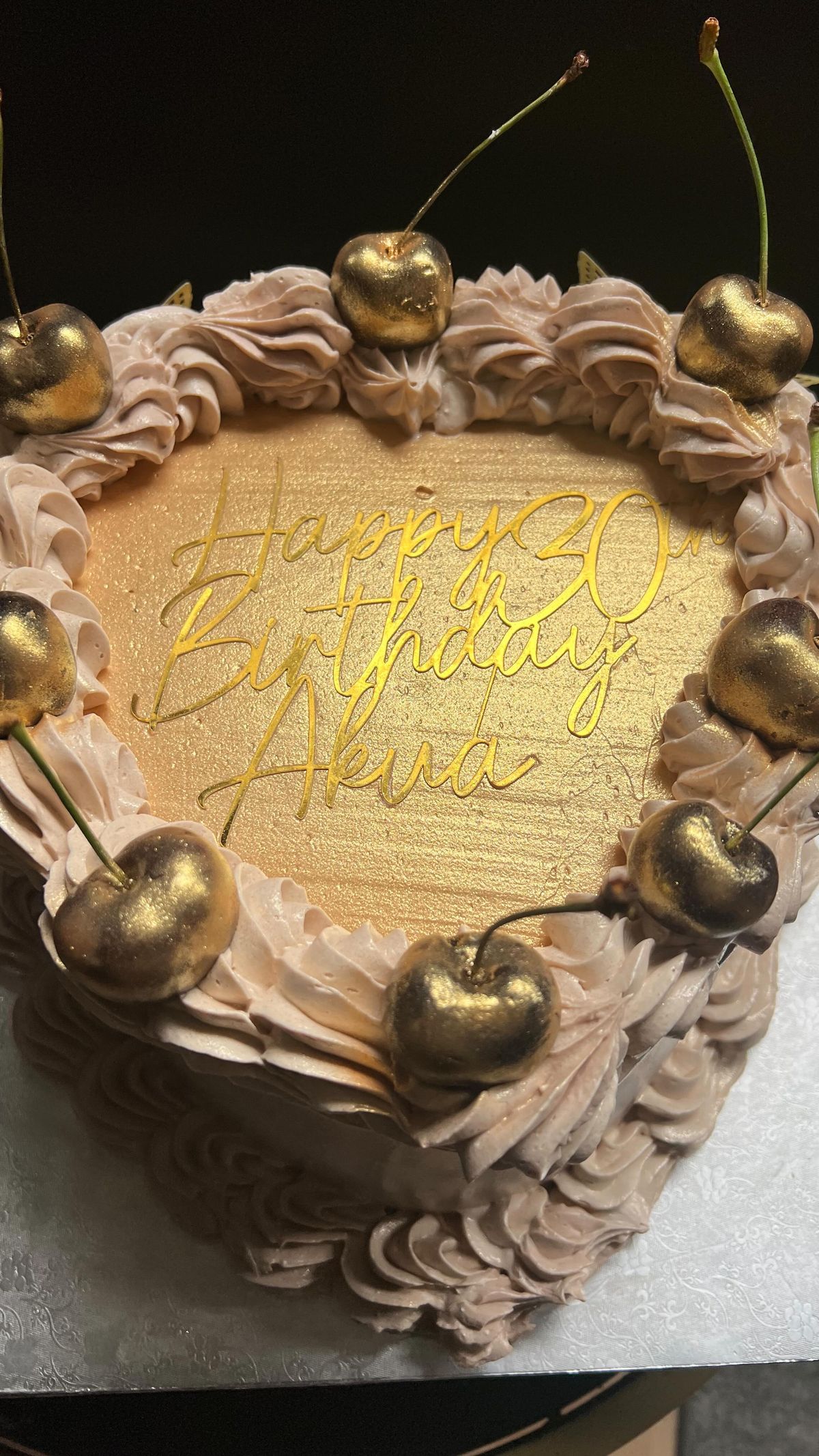 A gold heart-shaped 30th birthday cake topped with cherries